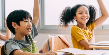 Deux élèves, une fille et un garçon, lèvent la main en classe