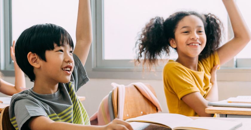 Deux élèves, une fille et un garçon, lèvent la main en classe