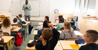 Dans une classe, un écolier lève le doigt
