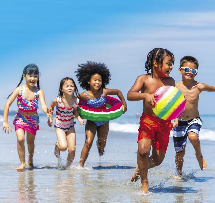5 enfants, garçons et filles, jouent à marée basse, les pieds dans l'eau