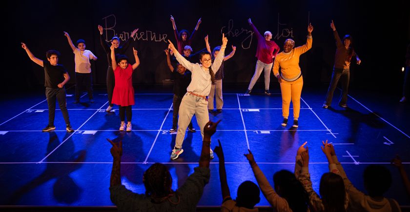 Programme de réussite éducative : Parents et enfants dansent les bras en l'air sur la scène du théâtre des Malassis
