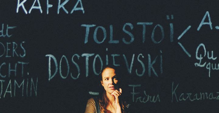 Audrey Vernon devant un tableau noir où sont insrcit des noms d'écrivains