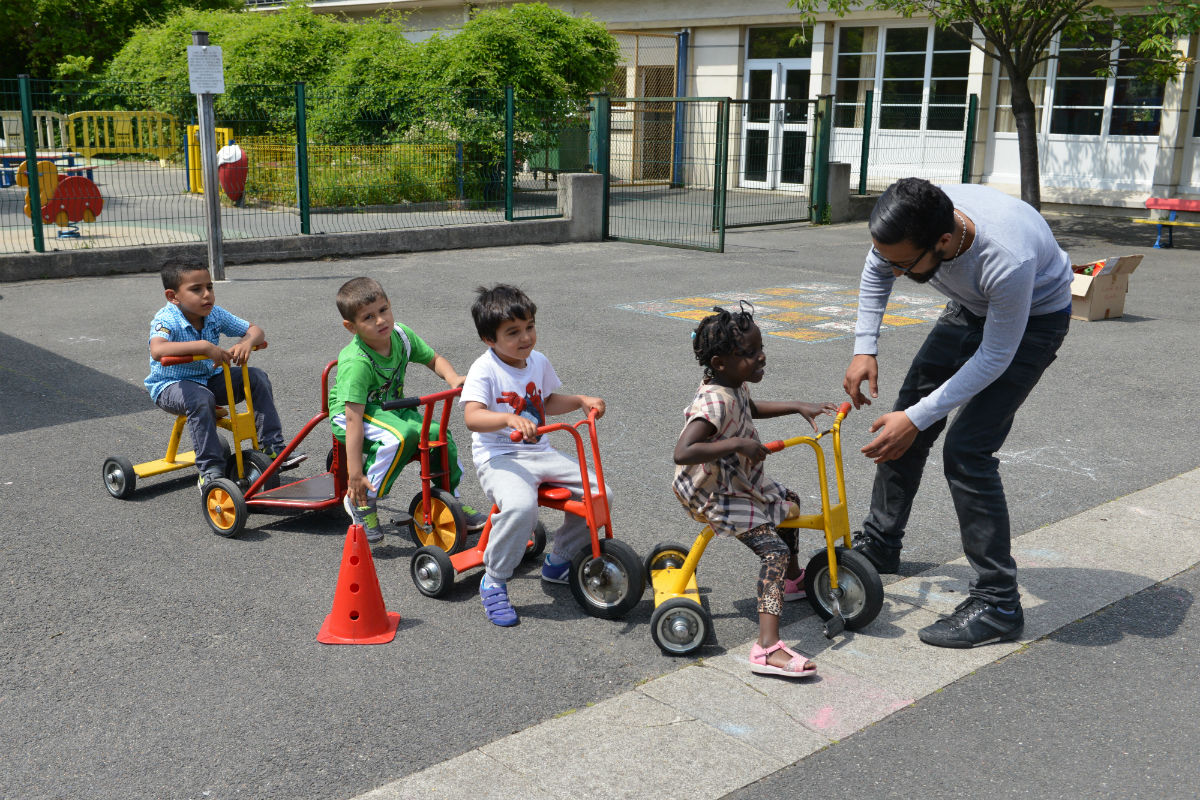 Des enfants font du tricycle guidé par un animateur
